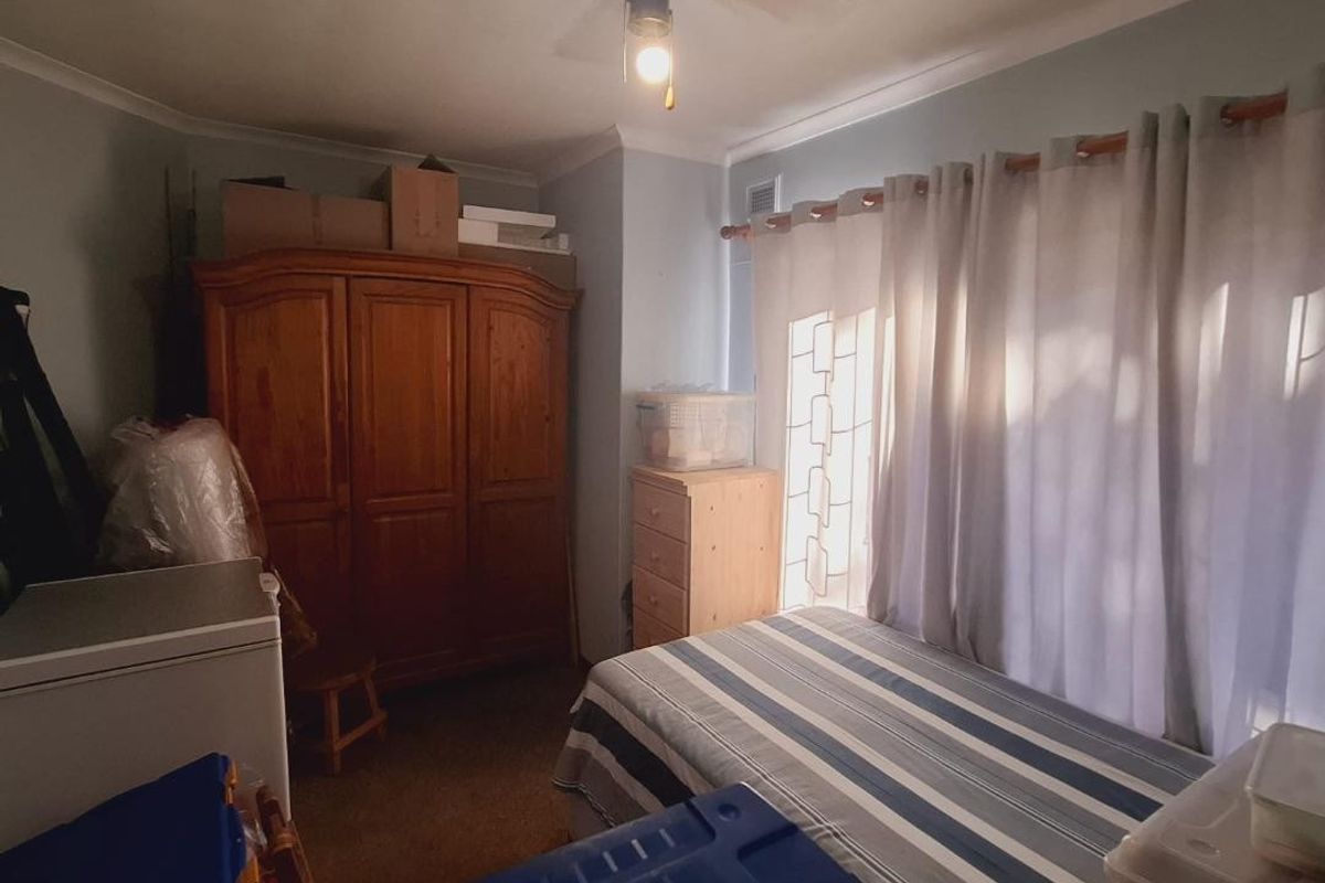 A bedroom featuring a ceiling fan and coving, currently used for storage with natural light filtering through window curtains.