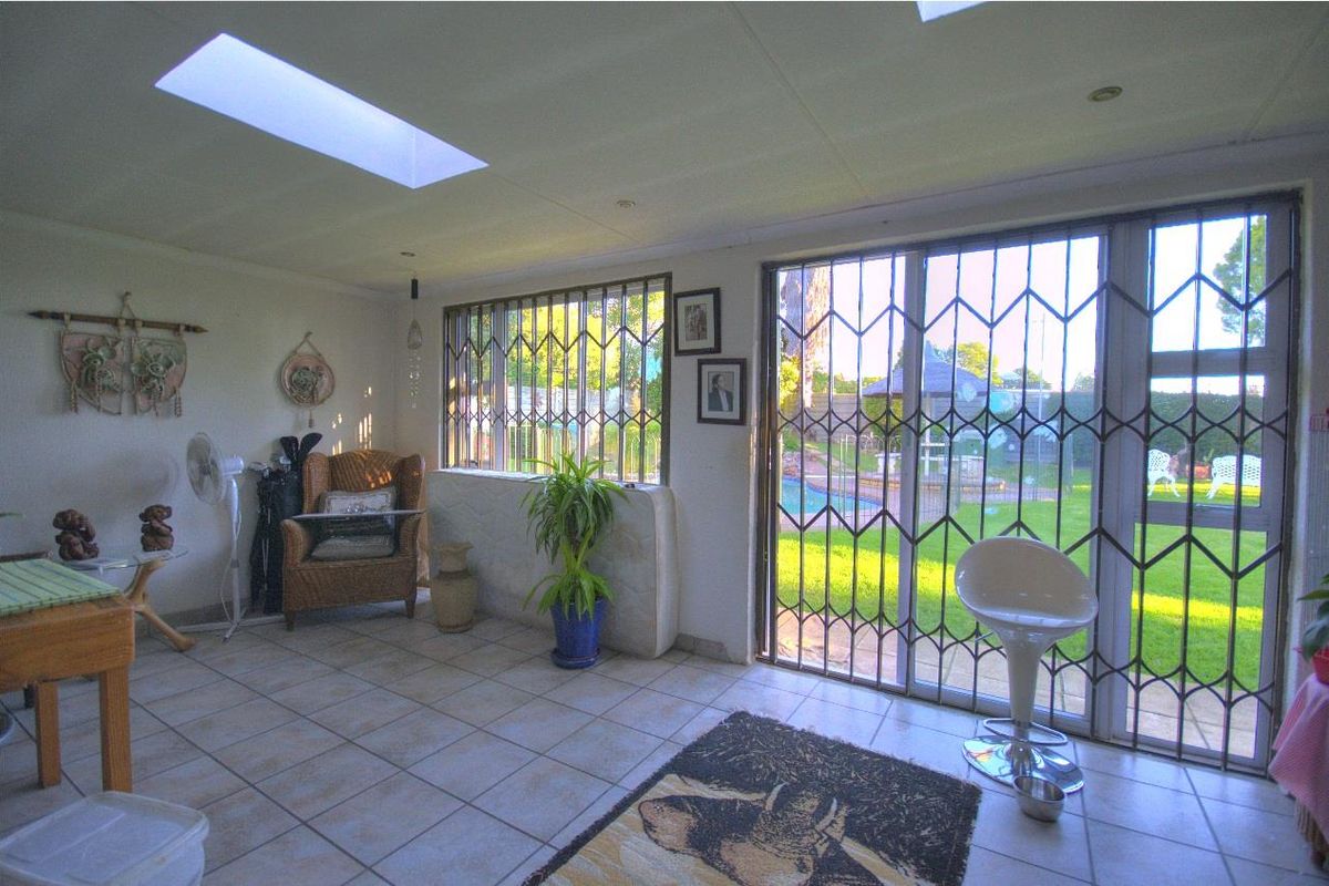 A bright living area featuring large skylights, tiled flooring, and security gates providing direct access to the garden and pool area.