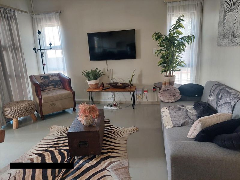 A living room featuring polished concrete floors and a wall-mounted television, with visible electrical cabling requiring tidying.