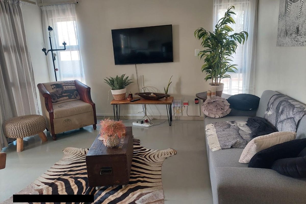 A living room featuring polished concrete floors and a wall-mounted television, with visible electrical cabling requiring tidying.