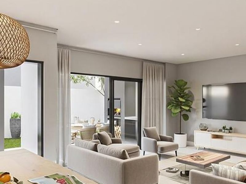Modern open-plan living area featuring recessed lighting, neutral finishes, and seamless access to an outdoor patio through large sliding glass doors.