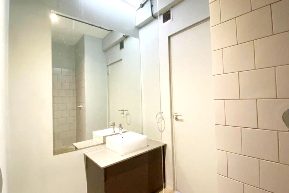 A modern bathroom featuring a vanity with a vessel sink, large wall mirror, and white subway-style wall tiling.