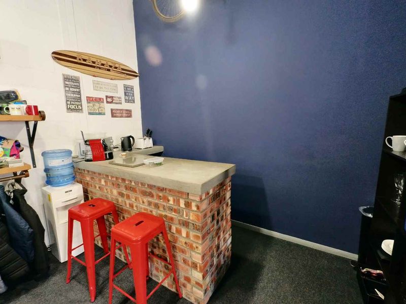 A small industrial-style bar area featuring a brick base with a concrete countertop, set against a dark blue accent wall.