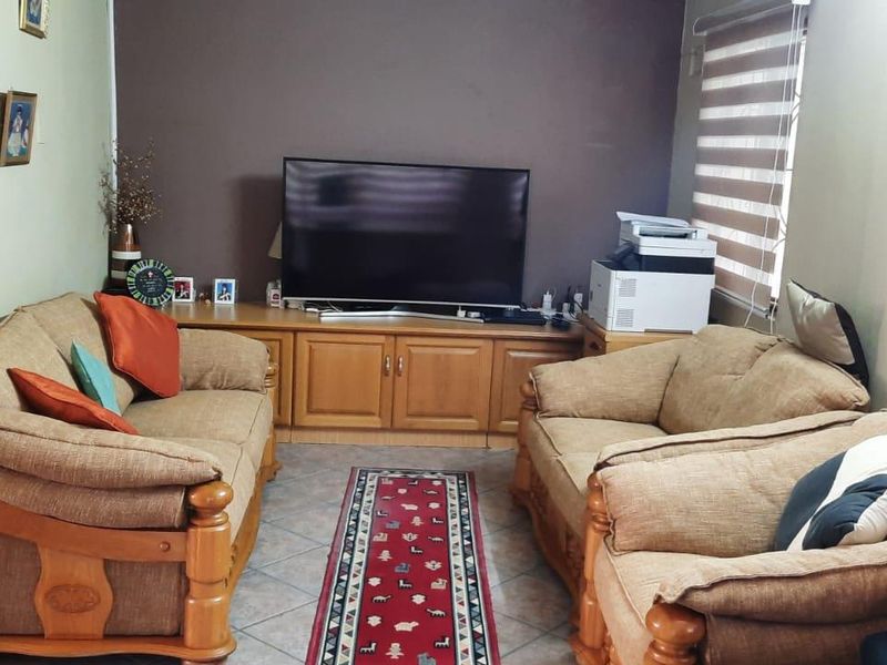 A comfortable living room featuring built-in cabinetry, tiled flooring, and roller blinds, providing a functional and well-maintained space for relaxation.