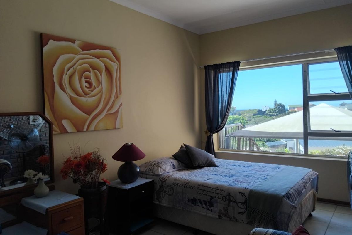 A bedroom featuring large windows with natural light and views, tiled flooring, and neutral wall finishes.