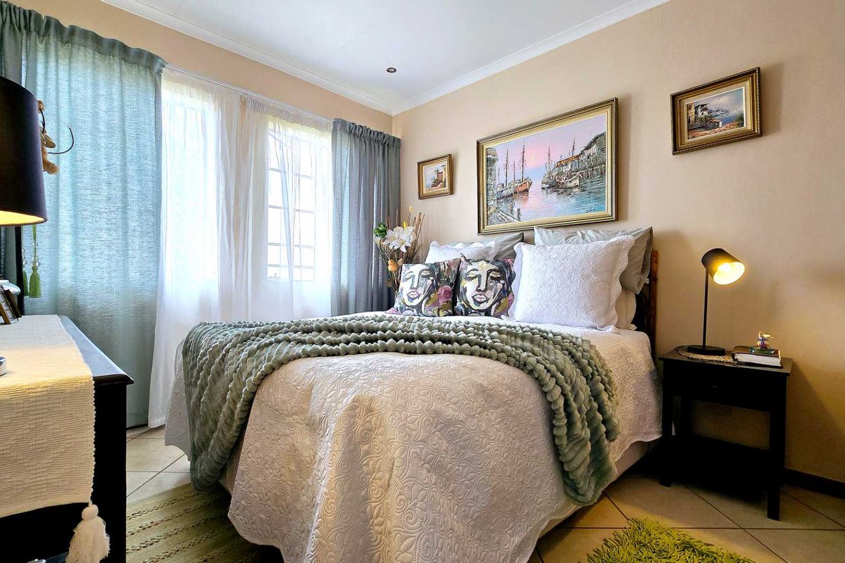 A well-lit bedroom featuring tiled flooring, neutral wall tones, and large windows that provide ample natural light.