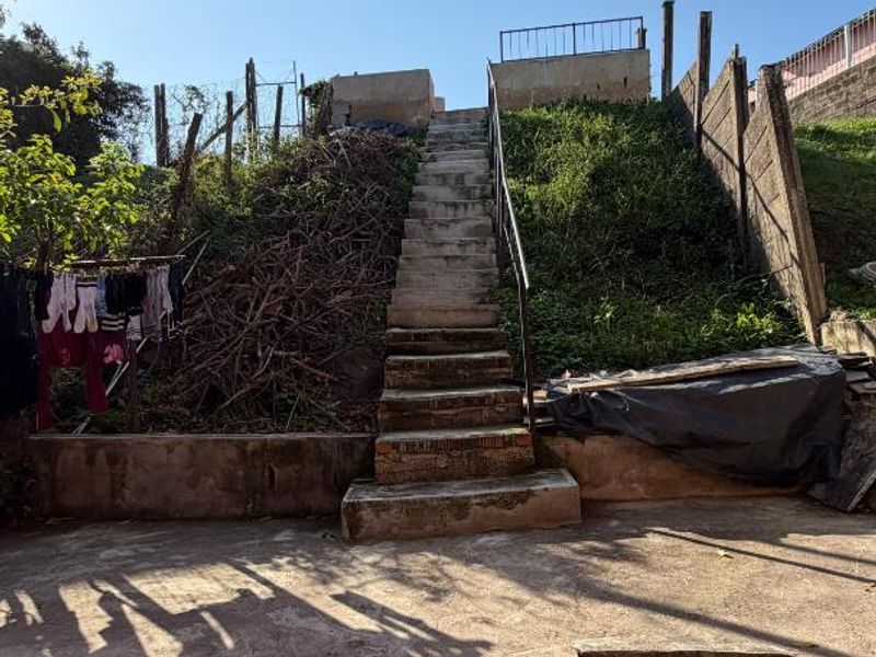 Rear outdoor area featuring concrete stairs leading to an elevated section, with weathered concrete surfaces and significant landscaping potential.