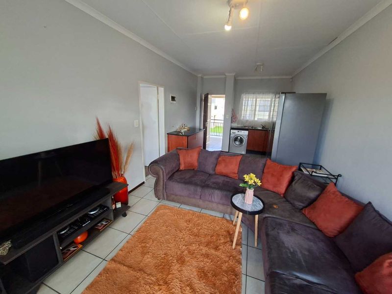 Open-plan living area featuring tiled flooring, integrated kitchen cabinetry with sink, and a dedicated laundry connection point.