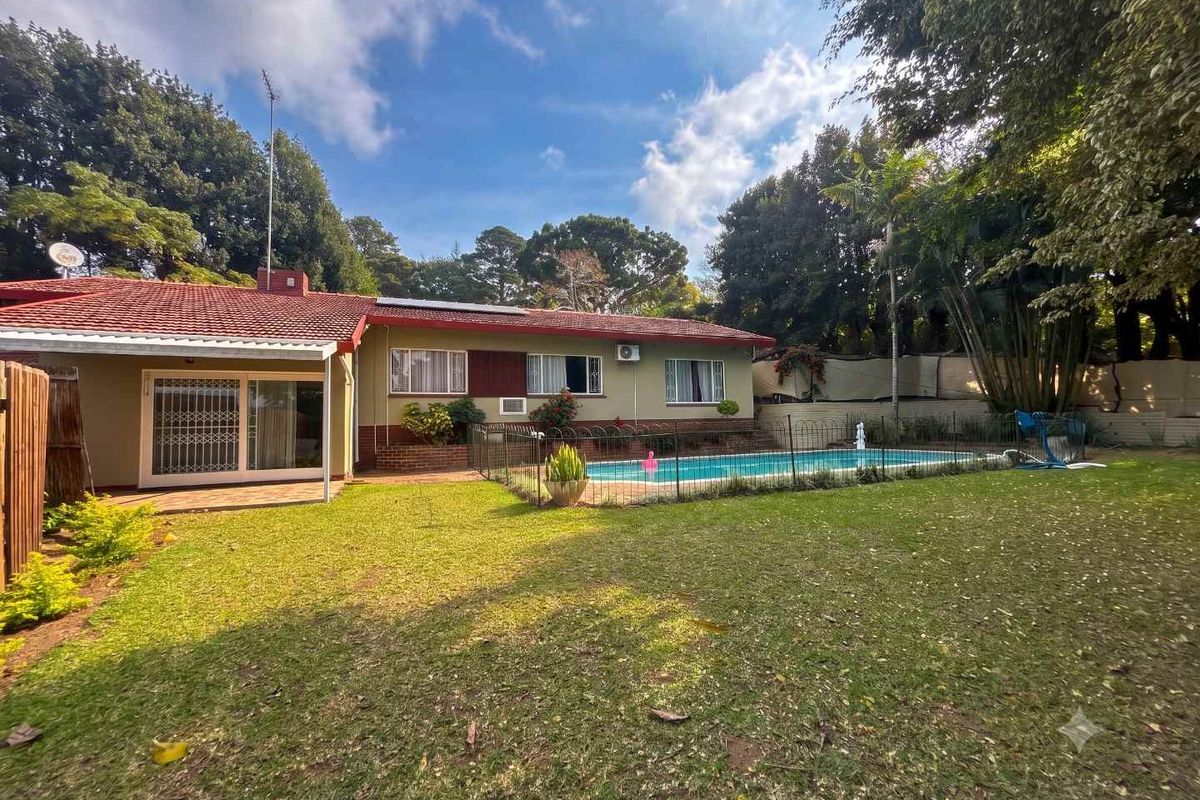 Rear view of the property featuring a swimming pool, landscaped garden, and a single-story dwelling with a tiled roof and sliding door access.