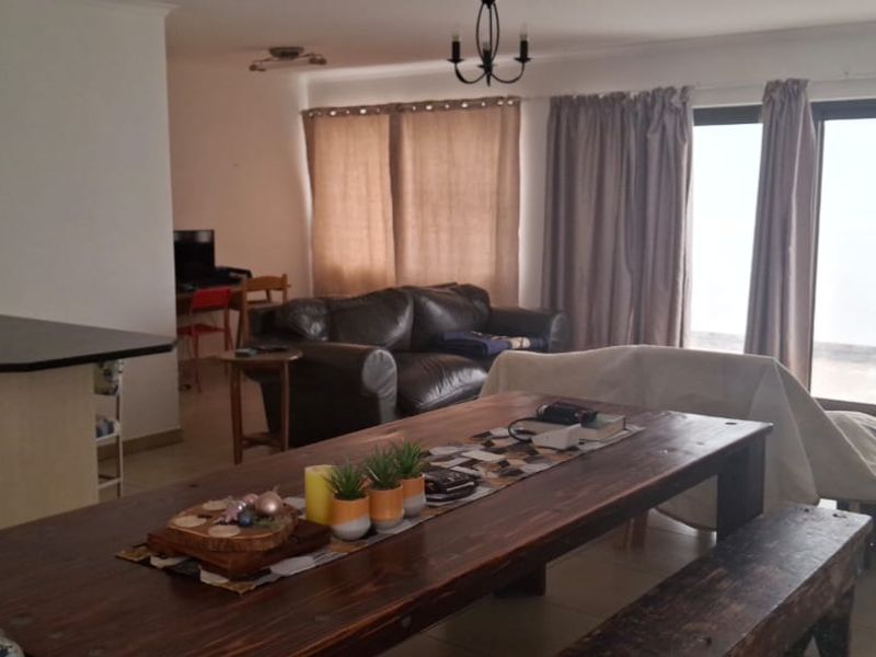 An open-plan living and dining area featuring tiled flooring and large sliding glass doors that provide access to the exterior.