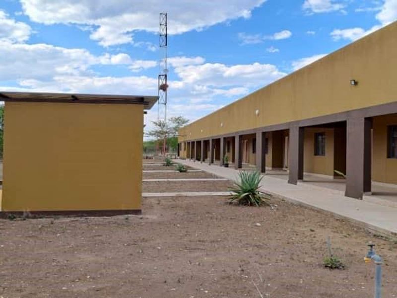 A view of the rear exterior of the farm building featuring a long covered walkway, exterior lighting, and a communication tower on the grounds.