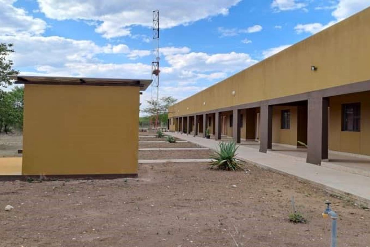 A view of the rear exterior of the farm building featuring a long covered walkway, exterior lighting, and a communication tower on the grounds.