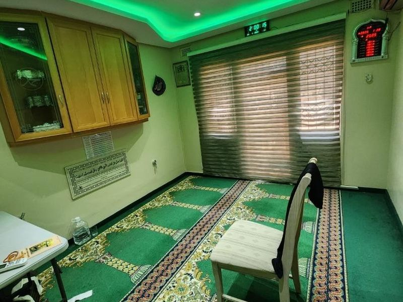 A multi-purpose room featuring recessed green accent lighting, built-in wooden cabinetry, and window blinds.