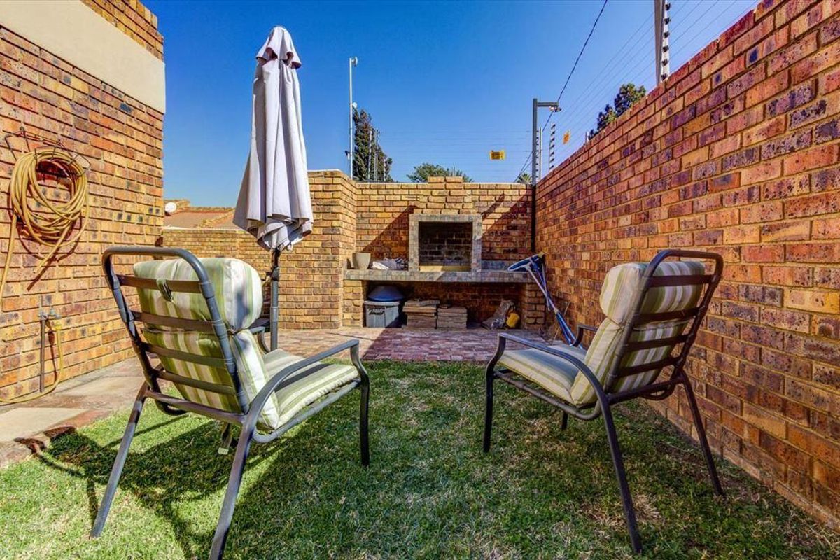 A private rear courtyard featuring a built-in brick braai area, enclosed by high brick boundary walls with integrated electric security fencing.