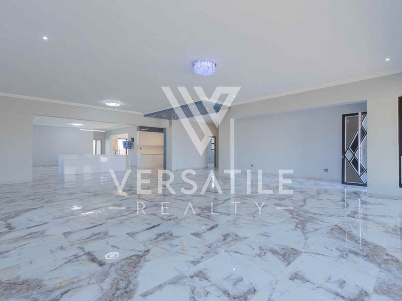 Spacious open-plan living area featuring high-gloss marble-look floor tiles, modern recessed lighting, and a decorative glass-paneled door.