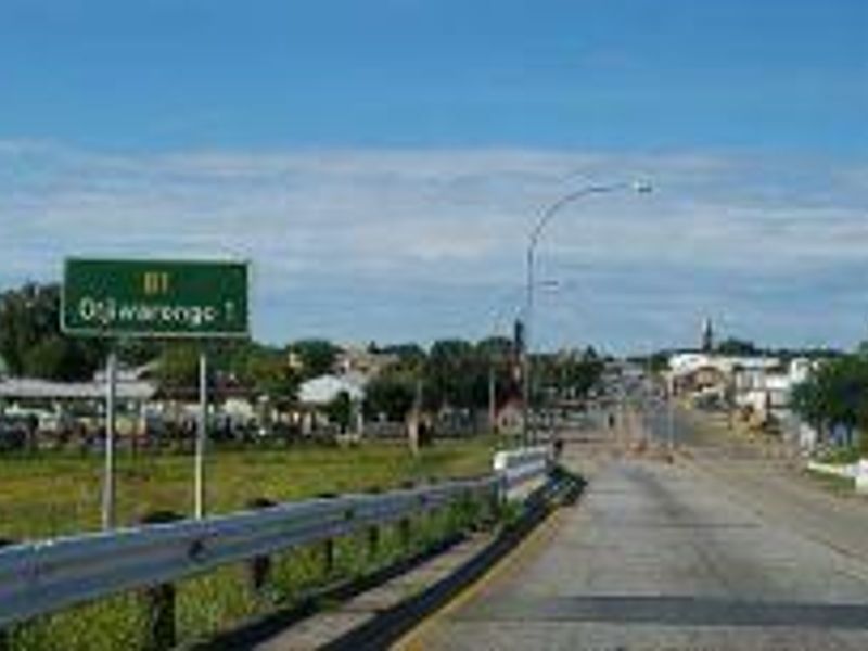 A view of the main road approach leading into the town of Otjiwarongo, featuring standard roadway infrastructure and directional signage.