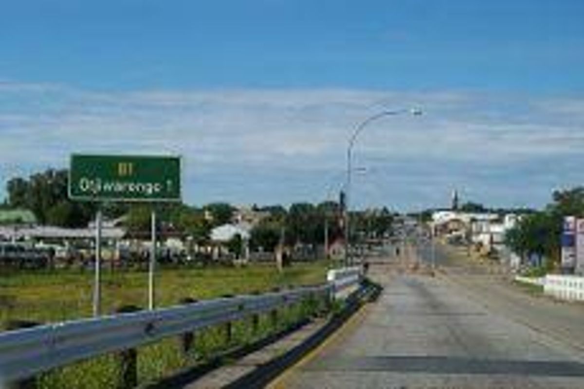 A view of the main road approach leading into the town of Otjiwarongo, featuring standard roadway infrastructure and directional signage.