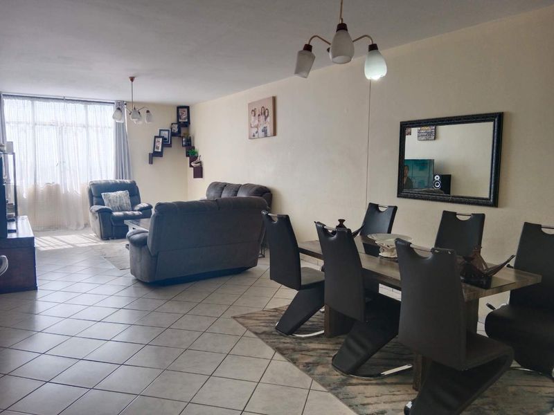 Spacious open-plan living and dining area featuring neutral wall finishes and ceramic floor tiles, offering a versatile layout for comfortable living.