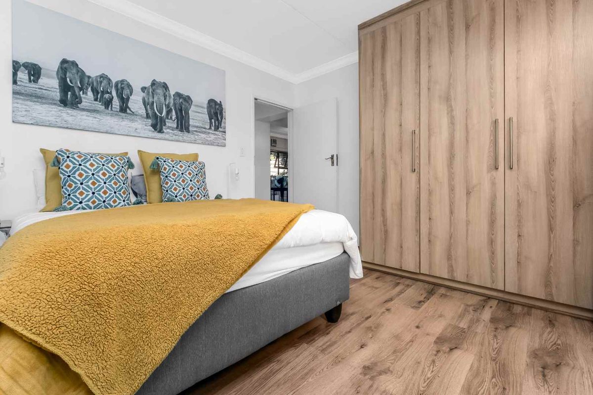 A well-maintained bedroom featuring light wood-tone built-in cupboards and modern laminate flooring.