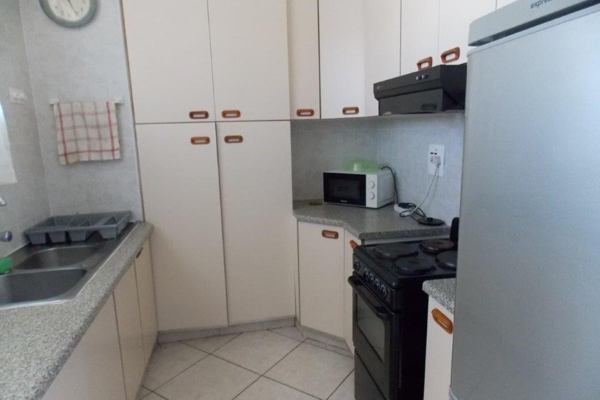 A functional kitchen featuring laminate cabinetry, granite-look countertops, a double bowl stainless steel sink, and tiled flooring.