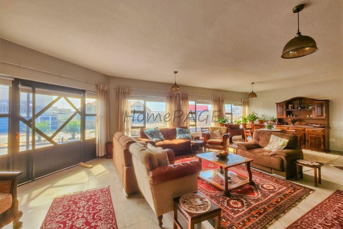Spacious living area featuring tiled flooring, large sliding glass doors providing natural light, and multiple pendant light fixtures.