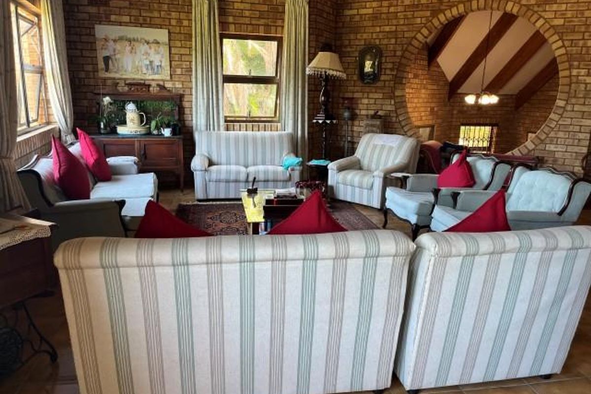 Spacious living room featuring exposed brick walls, tiled flooring, and a distinctive circular architectural opening leading to an adjacent area.