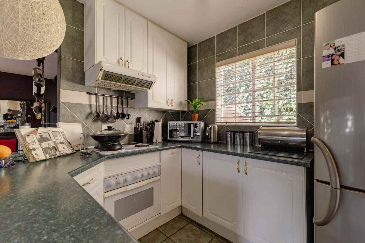 A functional kitchen featuring white cabinetry, dark laminate countertops, tiled backsplash, and built-in cooking appliances, offering a practical layout for daily meal preparation.