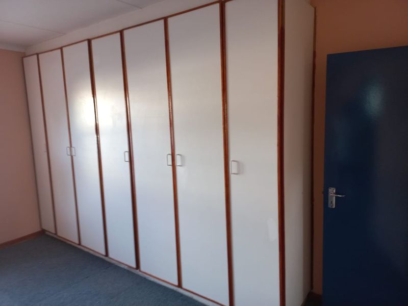 A bedroom featuring extensive floor-to-ceiling built-in cupboards with white doors and timber trim.