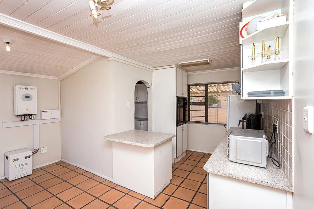 Functional kitchen featuring tiled flooring, built-in cabinetry, laminate countertops, and an integrated inverter and battery system for backup power.