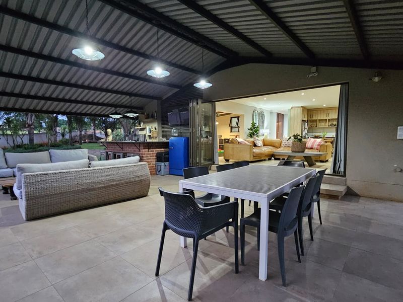 Spacious covered patio featuring tiled flooring, a built-in bar, and seamless indoor-outdoor flow through large sliding glass doors to the living area.