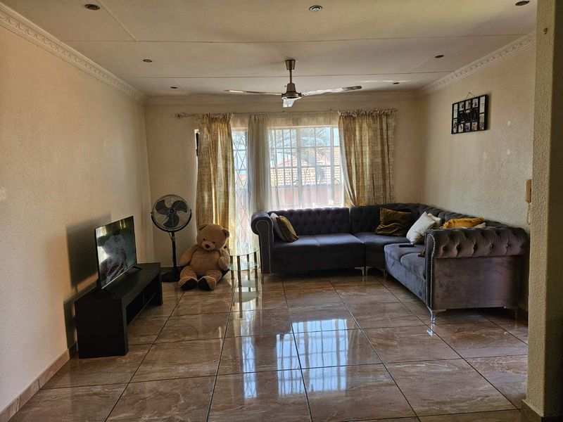 A living room featuring tiled flooring, recessed ceiling lighting, and a central ceiling fan, providing a functional and well-lit space.