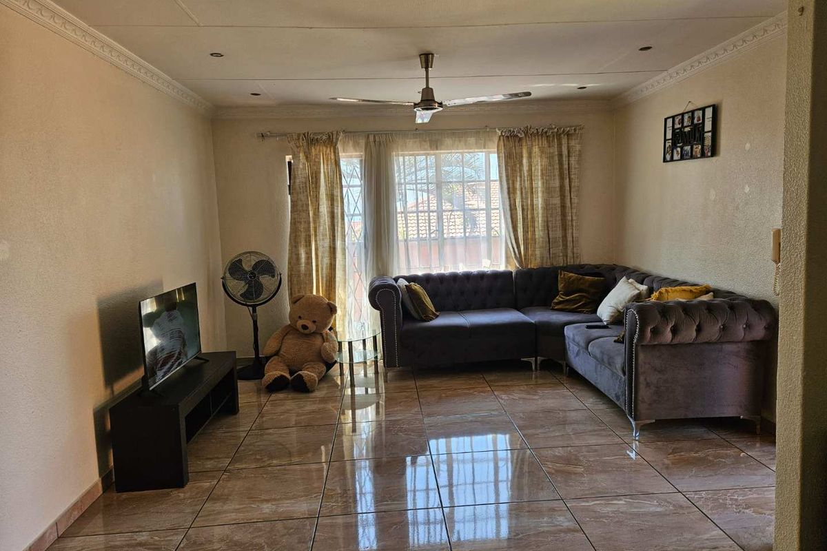 A living room featuring tiled flooring, recessed ceiling lighting, and a central ceiling fan, providing a functional and well-lit space.