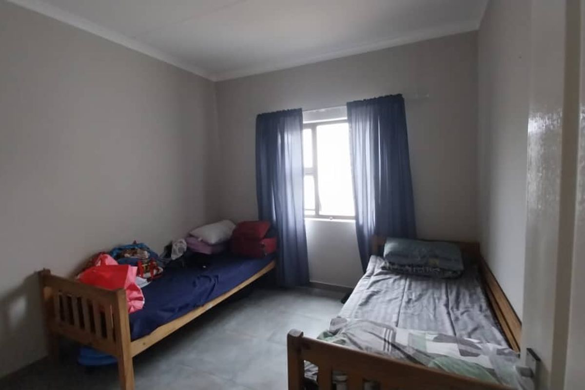 A functional bedroom featuring tiled flooring and a window with curtain tracks.