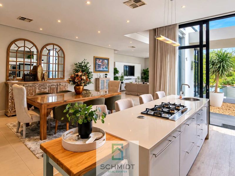 Spacious open-plan living and dining area featuring a modern kitchen with a central island, gas hob, and seamless flow to the outdoor patio.