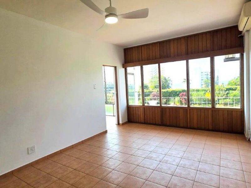 An empty living room featuring tiled flooring, a ceiling fan, split-system air conditioning, and large timber-framed windows with garden views.