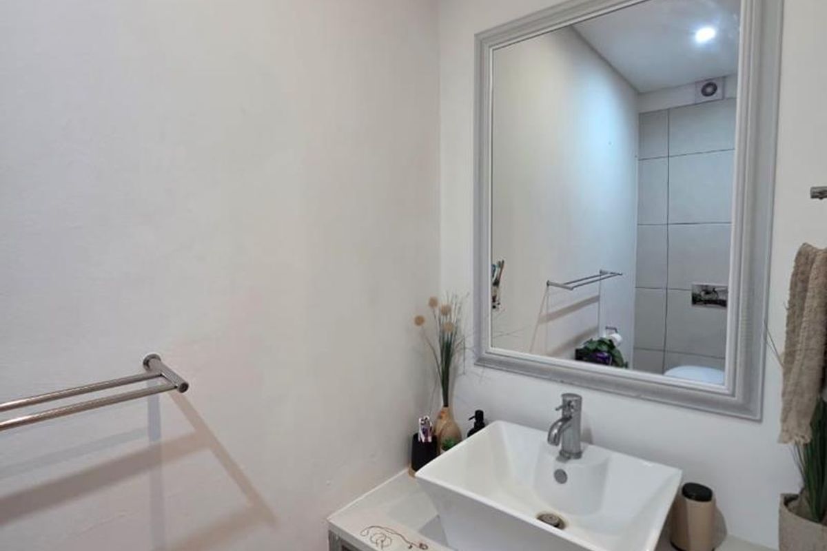 A modern bathroom featuring a vessel sink mounted on a floating vanity with a framed mirror and chrome towel rail.