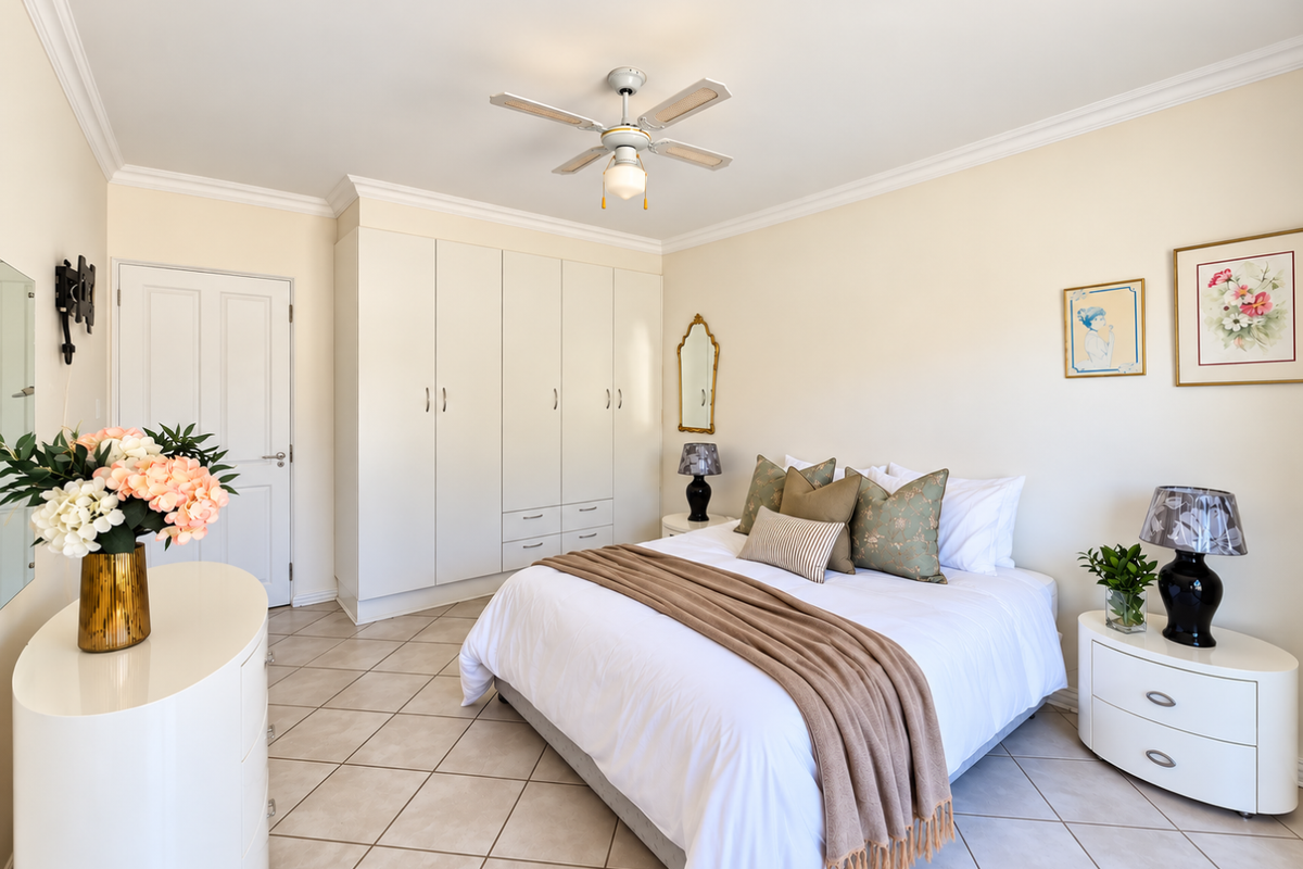 A well-maintained bedroom featuring neutral tiled flooring, built-in cabinetry, and a ceiling fan, offering a clean and comfortable living space.