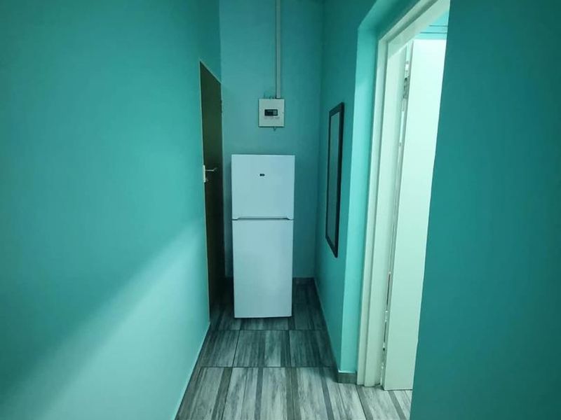 A narrow hallway featuring tiled flooring and painted walls, providing access to adjacent rooms within the cottage.