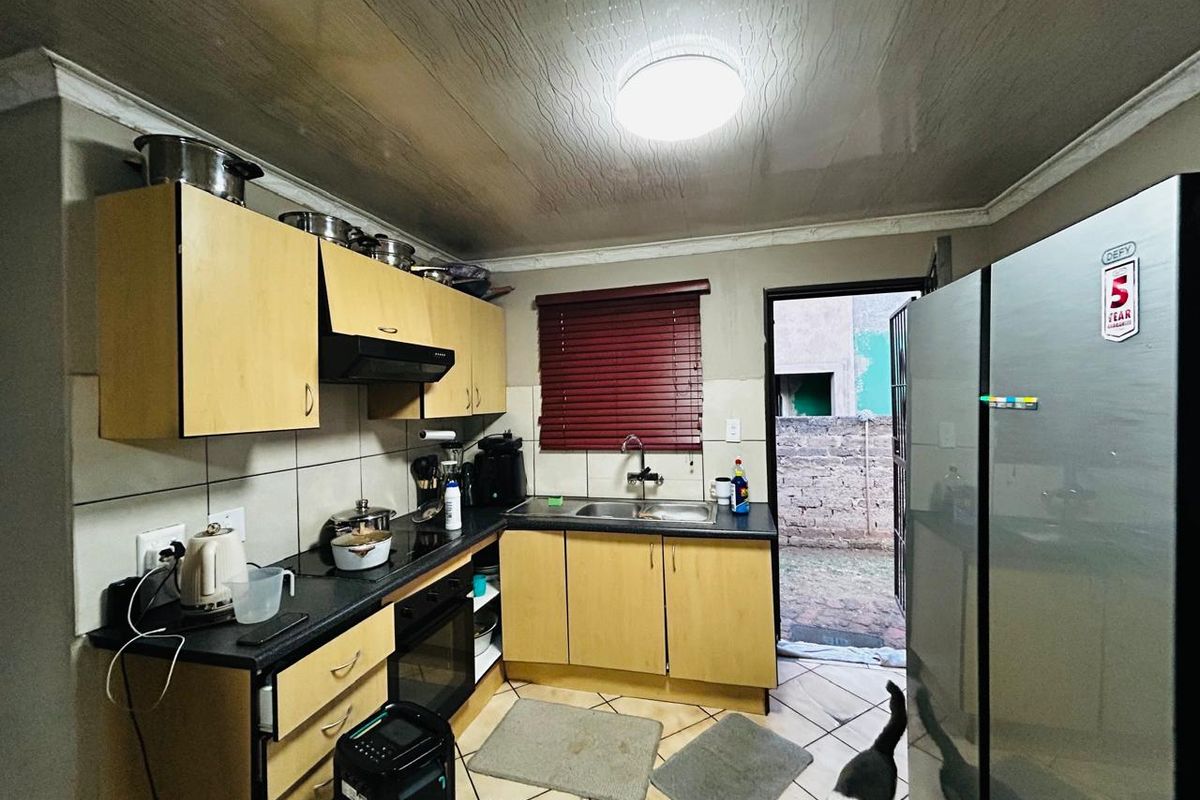 A functional kitchen featuring laminate cabinetry, tiled backsplash, and built-in oven, with direct access to the exterior rear area.