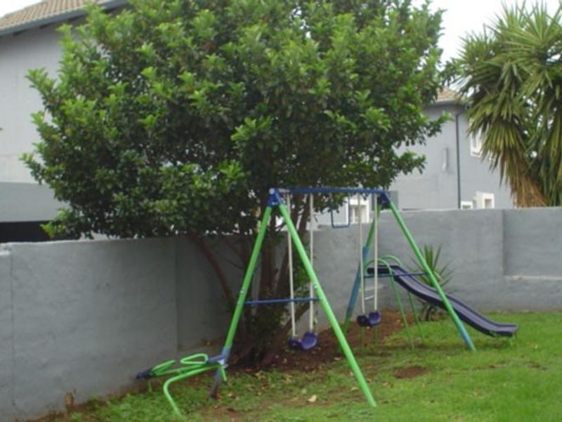 A rear garden area featuring a lawn and a perimeter boundary wall.