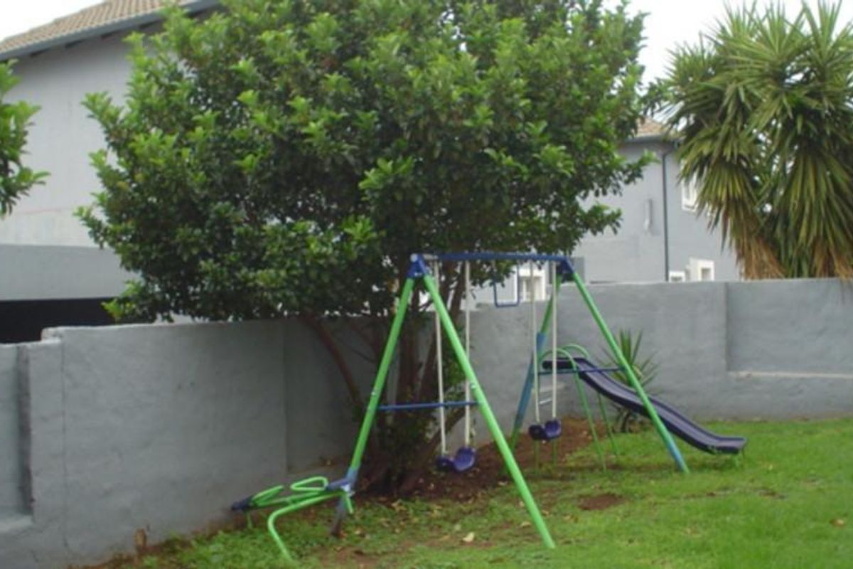 A rear garden area featuring a lawn and a perimeter boundary wall.