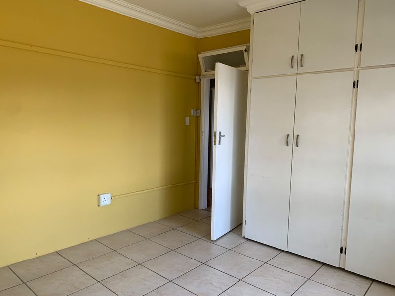 A vacant bedroom featuring built-in cupboards, tiled flooring, and a neutral layout, offering a blank canvas for personalization.
