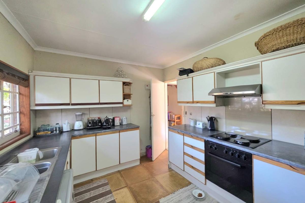 A functional kitchen featuring built-in cabinetry, laminate countertops, a double basin sink, and integrated cooking appliances including an oven, hob, and extractor fan.