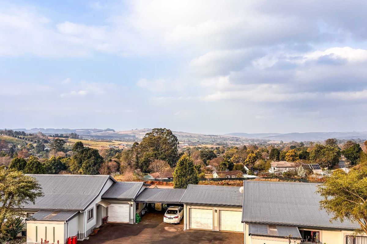 Aerial view of the property showing the main building structure, paved driveway, multiple garages, and expansive surrounding landscape views.