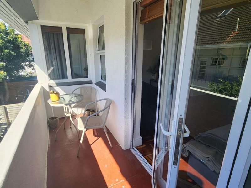 A compact balcony featuring a painted concrete floor and sliding glass door access to the interior living space.