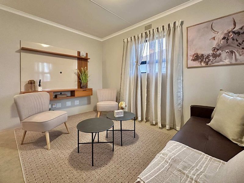 A well-maintained living room featuring a built-in media console, neutral wall finishes, and a window with curtain tracks.