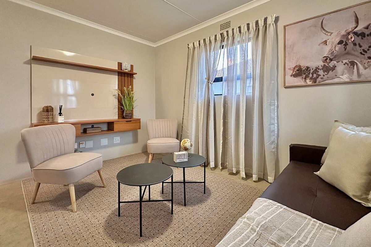 A well-maintained living room featuring a built-in media console, neutral wall finishes, and a window with curtain tracks.