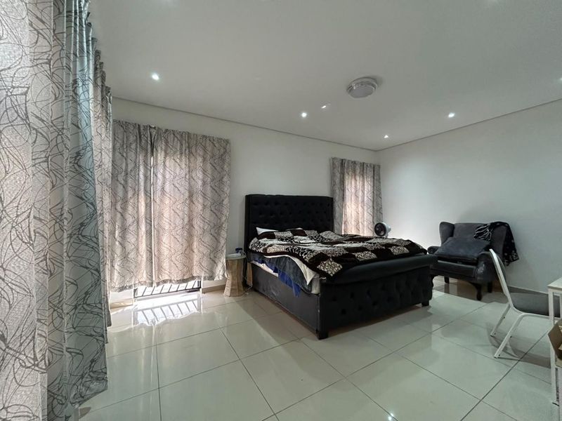 Spacious bedroom featuring neutral tiled flooring and recessed downlighting, providing a clean and well-maintained foundation for personal styling.