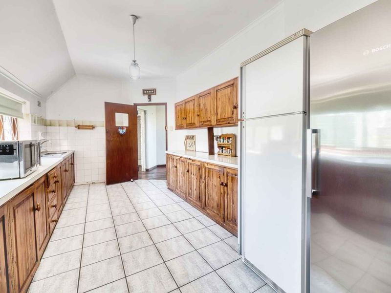 A functional kitchen featuring extensive wooden cabinetry, tiled flooring, and a tiled backsplash, offering a classic layout with ample storage space.