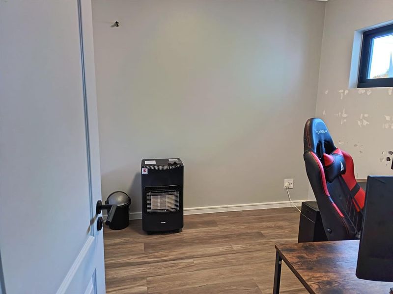 A bedroom featuring laminate flooring and a window, currently requiring wall repairs and finishing to complete the space.